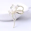 Detailed shot of bow-shaped brooch with white shell flowers, pearls and zircon crystals - Shell Flower Bow Style / Gold