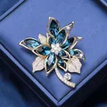 Broche florale élégante avec cristaux bleu foncé et diamants sur métal plaqué or rose - Bleu