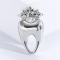 Detailed macro of a polished silver tooth brooch with a sparkling rhinestone crown design - Silver