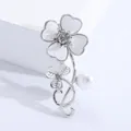 Detail of elegant silver clover brooch with white enamel petals and a central rhinestone - Silver