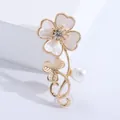 Macro detail of elegant flower brooch with shell petals, crystal center and a pearl drop - Gold