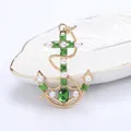 Golden nautical anchor brooch with green crystals and pearls on white tray - Green