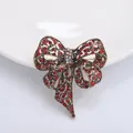 Vintage bronze bow brooch with red rhinestones and hollow floral metal patterns - Red
