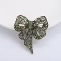 Elegant vintage gold bow brooch with sparkling green rhinestones and hollow-out metalwork - Green