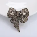 Spilla a fiocco vintage in oro antico con strass champagne su un elegante piatto bianco - Marrone