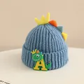 Detail of baby dinosaur knit hat featuring soft blue fabric and colorful back spikes - 2-6 Years Old / Blue