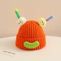 Close-up of bright orange knitted kids beanie with fuzzy pom-poms and funny 3D antennae - Baby Approx 2-6 Years / Orange