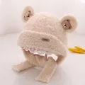Detailed close-up of beige plush earflap hat with bear patch and fuzzy texture - One Size / Deep Beige