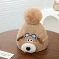 Detail van gebreide babymuts met puppy-oren, zachte pompon en geribbelde textuur afwerking - Khaki