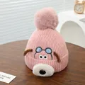 Detail van roze gebreide babymuts met schattig hondenborduurwerk en een zachte roze pompon - Roze