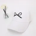 Dettaglio del berretto bianco in mesh con ricamo a fiocco nero e retro traspirante - Taglia per Bambini / Bianco