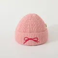 Detail of pink knitted beanie featuring a fuchsia bow embroidery and branded side label - Baby Approx 2-6 Years / Pink