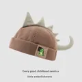 Brown corduroy dinosaur hat for children featuring a cute plush tail and green fins - Baby Size / Light Coffee