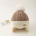 Close-up of kids knitted hat with pom pom, cable knit texture and Choco badge detail - One Size / Coffee