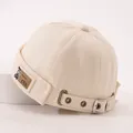 Detail der beige Baumwoll-Docker-Mütze mit braunem Leder-Bären-Patch und Metallschnalle - 50-52CM / Beige
