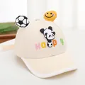 Detail showing the 3D football and smiley face ornaments on a beige kids' baseball cap - Beige