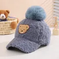 Detail view of plush blue baby baseball cap with fur pompom and cartoon bear patch - 50-54cm / Blue