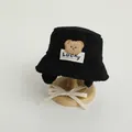 Detail of black sherpa bucket hat featuring a plush bear patch and Lucky label for kids - 48-52cm / Black