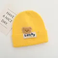Dettaglio macro del berretto in maglia giallo con toppa orso e etichetta Lucky - Bambini 2-6 Anni Elastico / Giallo Zenzero