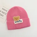 Dettaglio del berretto in maglia rosa per neonati con toppa a orsetto e etichetta Lucky - Bambini 2-6 Anni Elastico / Rosa Antico