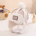 Beigefarbene Kinder-Fliegermütze mit Kunstpelzbesatz, Bommel und verstellbarem Riemen - Hellbeige