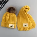 Detail der gelben Strickmütze und Schal Set mit V-Label und braunem Kunstpelz-Bommel - Kinder Alter 2-7 Set / Gelb