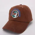 Close-up of brown corduroy kids cap featuring a green cartoon dinosaur embroidery patch - Style 2 / Coffee
