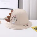 Close-up of cotton sun hat featuring cartoon dinosaur embroidery and textured spines - Kids Size / Beige