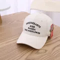 Beige katoenen kinder honkbalpet met zwart borduursel op een houten bureau geplaatst - Kinderen Eén Maat / Beige