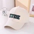 Close-up of green KUDE letter embroidery on cream cotton baseball cap for kids - 50-54cm / Beige