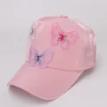 Detailed view of pink satin baseball cap with 3D butterfly embroidery and silky fabric - Pink Fabric