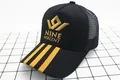 Détail du logo Nine Percent brodé sur casquette de baseball trucker en maille jaune et noir - Enfants (2-8 ans) / Noir Or
