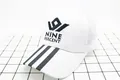 Gros plan sur la casquette trucker en mesh blanc avec broderie NINE PERCENT et rayures noires - Enfants (2-8 ans) / Blanc avec étiquette noire