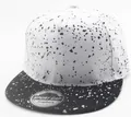 Detail der Snapback-Kappe mit schwarz-weißem Spritzmuster und silbernem Laser-Sticker - Weiß