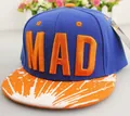 Detalle del bordado MAD y estampado de salpicaduras naranjas en visera de gorra azul - Naranja + Azul Real