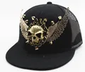 Détail d'une casquette punk avec tête de mort dorée, ailes et clous métalliques - Style maille