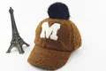 Dettaglio cappello in pile marrone con toppa M bianca e pompon di pelliccia sintetica - Bambini (3-8 anni) / Marchio M Caffè