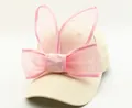 Détail d'une casquette en coton beige avec oreilles de lapin en tulle et nœud rose - Beige