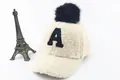 Close-up of beige fleece kids baseball cap with black pompom and letter A embroidery - Children (3-8 Years Old) / A Marker White