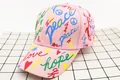 Close-up of pink cotton baseball cap with colorful graffiti and peace love embroidery - Kids (3-12 Years) / Letter Pink