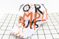 Close-up of kids baseball cap with orange and black street graffiti print on white canvas - Kids / MPL White