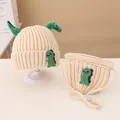 Knitted baby set with cream white hat and bib featuring green dinosaur 3D patch - Knitted Hat And Bib Set / Beige
