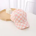 Close-up of pink checkered baseball cap with white smiley face patterns and canvas texture - Kids / Pink