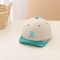 Dettaglio del cappellino da neonato con ricamo della lettera R e visiera morbida verde - Neonato / Tesa Verde
