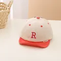 Dettaglio del cappellino bimbo con lettera R ricamata rossa e visiera arancione - Neonato / Falce Arancione