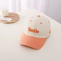 Nahaufnahme der Smile-Stickerei und des kontrastierenden Schirms der Kinderkappe - Kinder (3-10 Jahre) / Beige und Orange