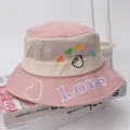 Close-up of pink mesh sun hat for kids featuring LOVE embroidery and heart patterns - Pink
