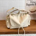 Minimalistische beige Messenger-Tasche aus Canvas mit breitem Gurt und Reißverschlusstaschen - Gebrochenes Weiß