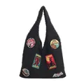 Black plush tote bag featuring colorful embroidered badges and soft lambskin texture - Black