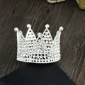 Detailed view of silver cake crown with white rhinestones on black stand and wood table - Silver